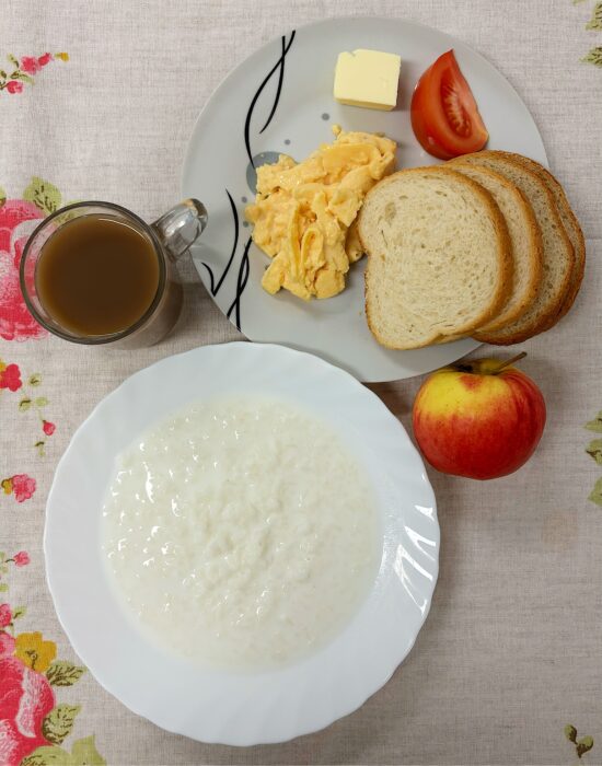 Ryż na mleku, pieczywo, masło, jajecznica, pomidor, jabłko i kawa z mlekiem.